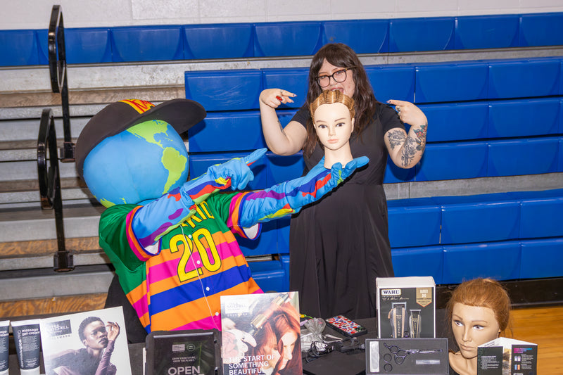 kooli holding braided doll head at college fair with attendee