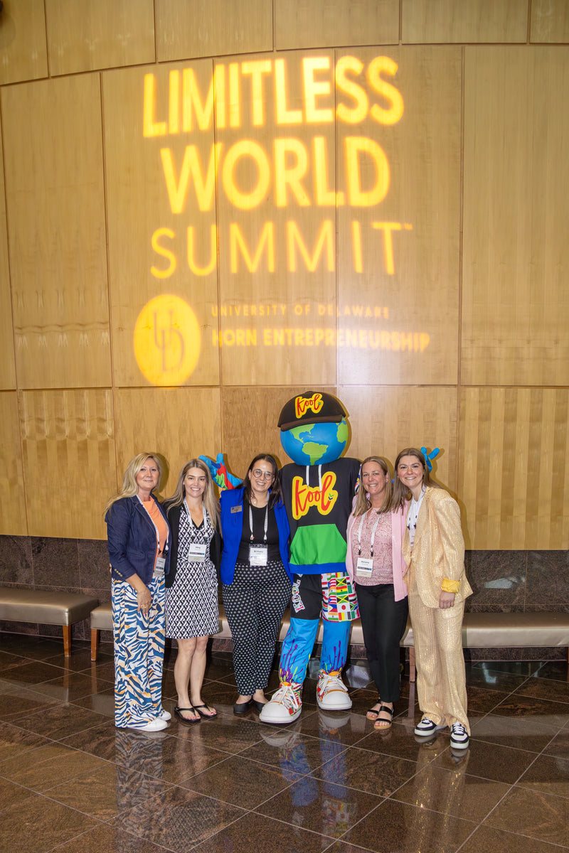 Group of people posing with kooli in front of a 'Limitless World Summit' sign.