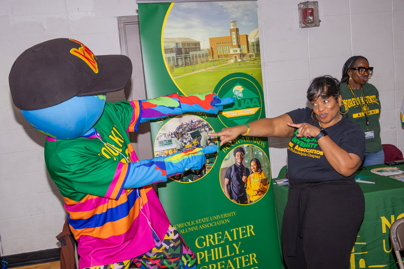 kooli interacting with a woman at college fair event with a banner in the background.