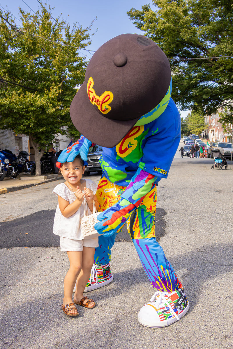 kooli greets a young smiling girl on a street. 