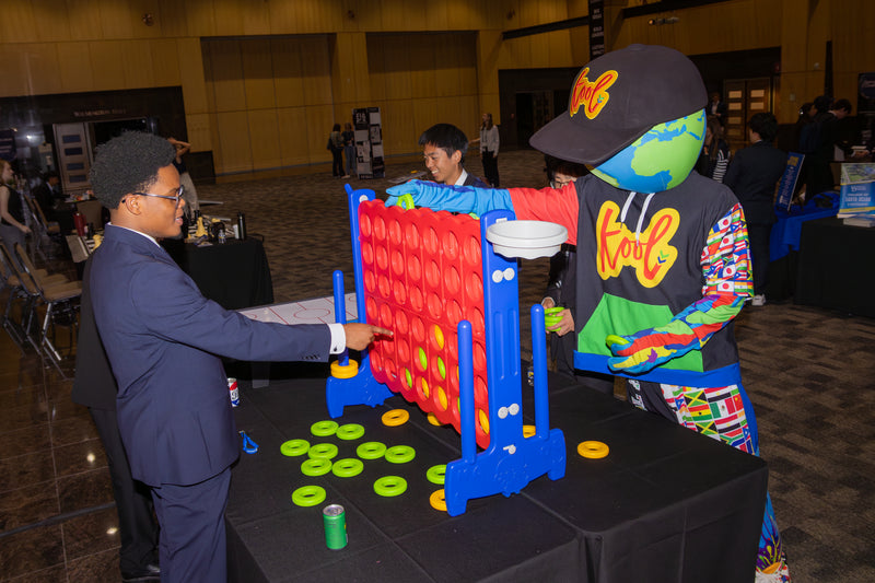 Person in a suit interacting with kooli playing connect four at the limitless world conference.