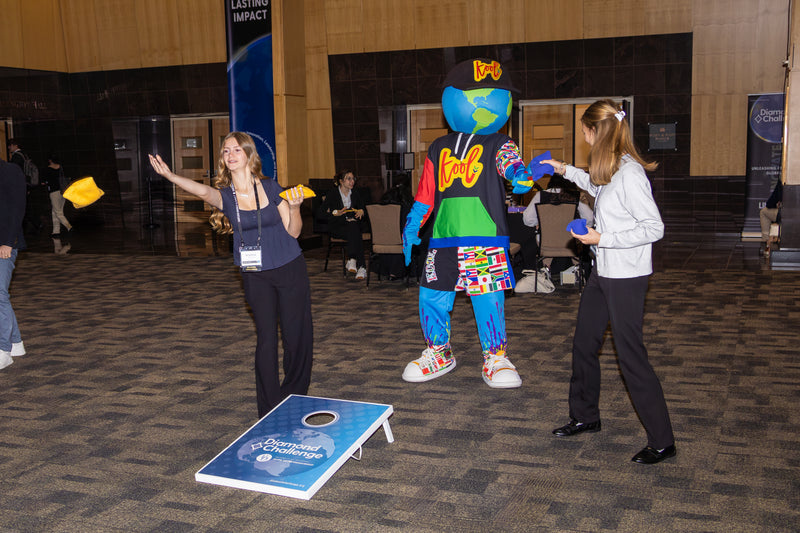 Two people playing cornhole with a kooli in a indoors at the limitless world conference