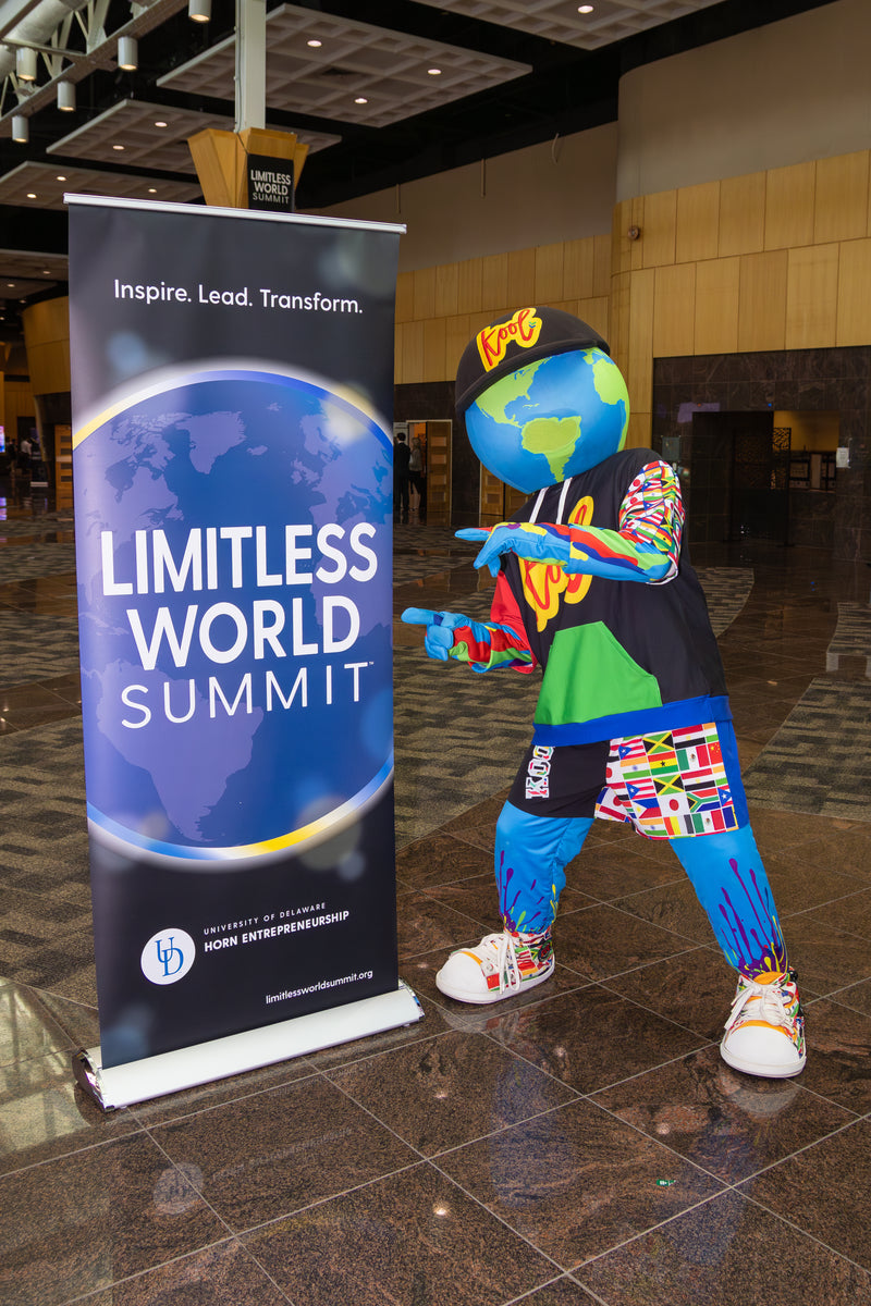 kooli standing next to a 'Limitless World Summit' banner at conference