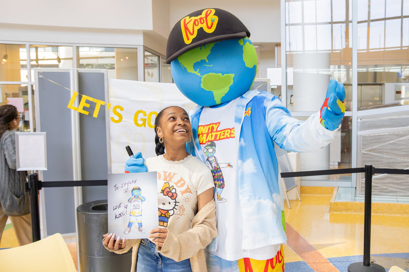 kooli posing with girl holding kooli signed headshot at nemours banana event party