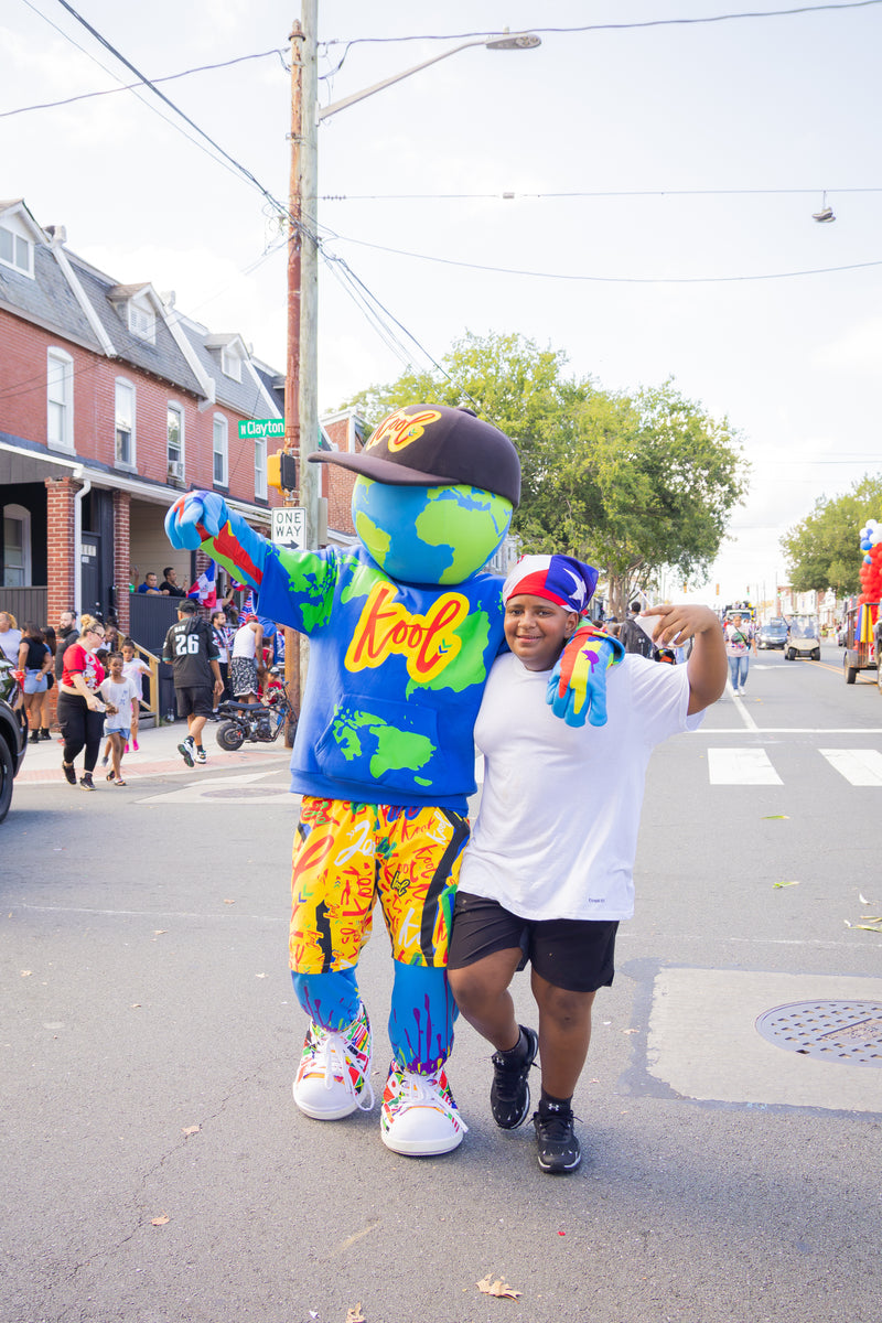 kooli in street wearing a  'kool' on the chest hoodie, on a city street during a parade.