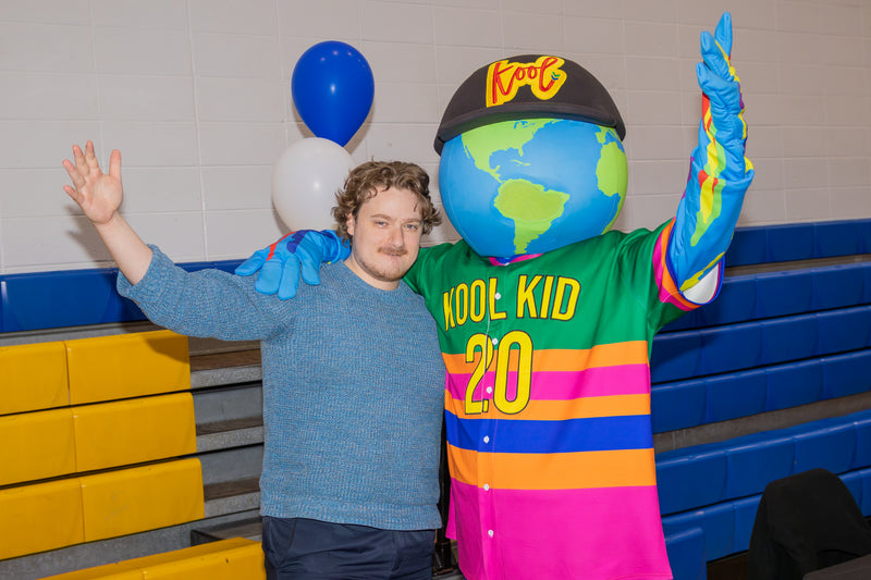 kooli posing with guest at college fair event with bot hands raised