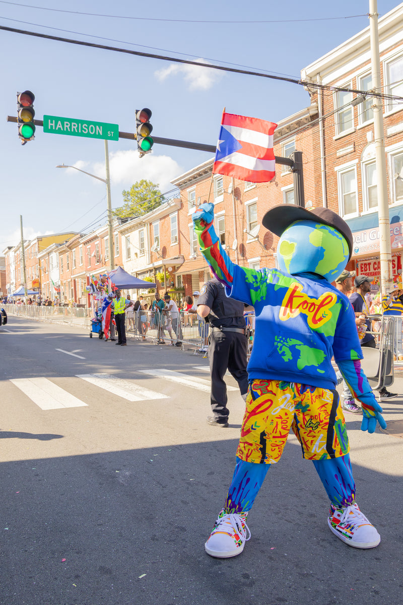 kooli stands on a city street holding a Puerto Rican flag. 