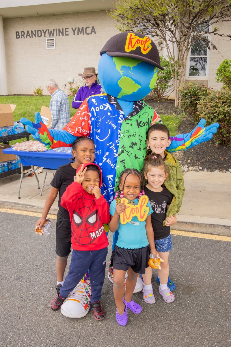 Children posing with kooli in front of a building labeled 'Brandywine YMCA'.